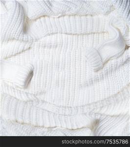 Background of white knitted blanket with sweater sleeves . Top view. Flat lay. Cold weather season layout. Insta style. Modern