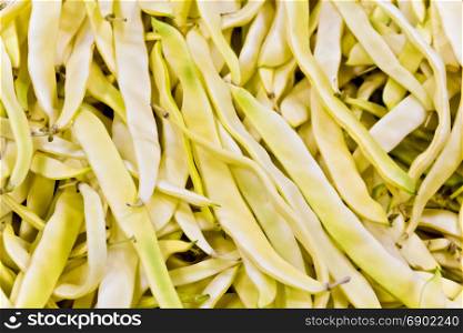 Background of yellow pods kidney beans on counter in market place