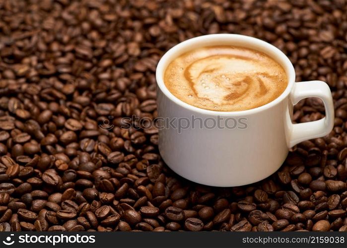 Background or texture made of roasted brown coffee beans.. Cup of espresso coffee on Background made of roasted brown coffee beans