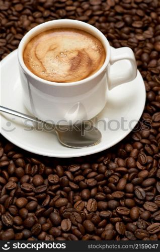 Background or texture made of roasted brown coffee beans.. Cup of espresso coffee on Background made of roasted brown coffee beans