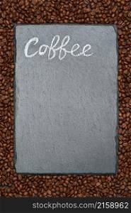 Background or texture made of roasted brown coffee beans and stone serving board with chalk handwritten sign.. Background or texture made of roasted brown coffee beans and stone serving board with chalk handwritten sign