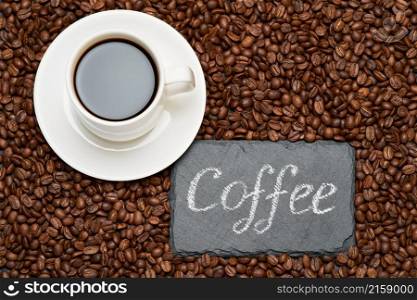 Background or texture made of roasted brown coffee beans and stone serving board with chalk handwritten sign.. Background or texture made of roasted brown coffee beans and stone serving board with chalk handwritten sign