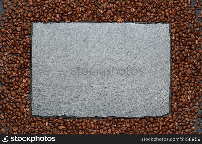 Background or texture made of roasted brown coffee beans and stone serving board.. Background or texture made of roasted brown coffee beans and stone serving board