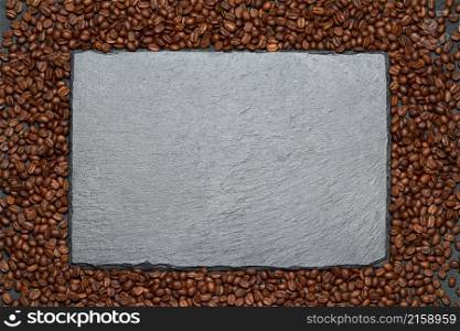 Background or texture made of roasted brown coffee beans and stone serving board.. Background or texture made of roasted brown coffee beans and stone serving board
