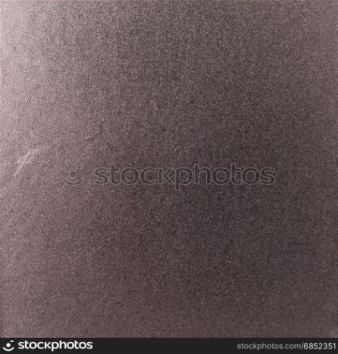 Background texture of a shiny metal sheet with a rough stippled textured surface reflecting light. Metal texture