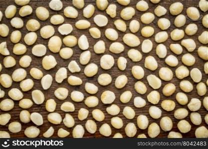 background texture of shelled macadamia nuts on rustic weathered wood - top view