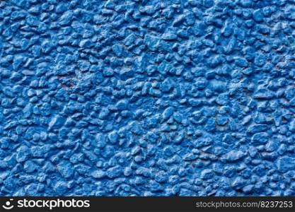 Background texture of small pebbles painted with blue paint. Stones fastened with a solution on a wall at home. Horizontal.