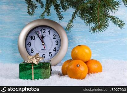 Background with a gift box and tangerines on snow and a clock.