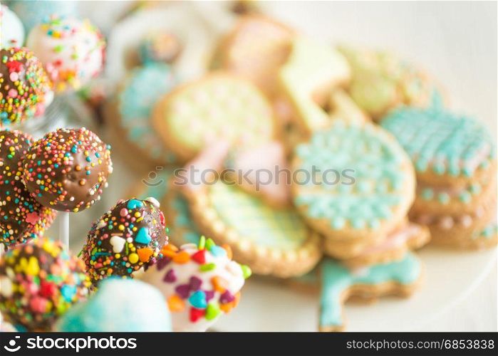 Background with colorful cookies and cake pops on white wooden desk