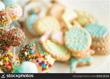 Background with colorful cookies and cake pops on white wooden desk