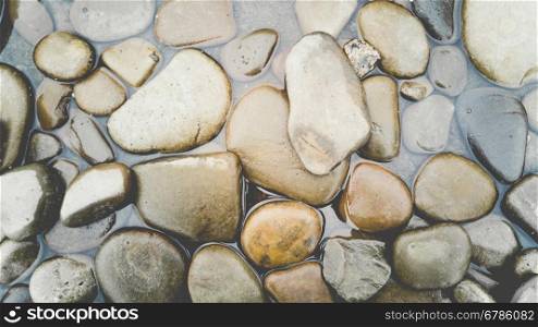 Background with colorful pebbles lying in water