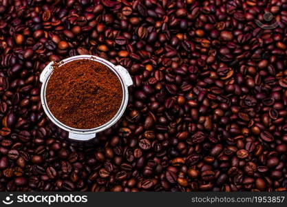 Background with ground coffee in portafilter surrounded by roasted coffee beans,