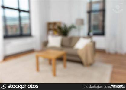 backgrounds and interior concept - blurred photo of tidy living room with cushioned sofa and table at home. interior of home living room with sofa and table