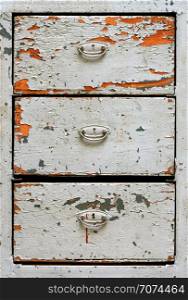 Backgrounds and textures: front surface of very old painted wooden drawers cabinet, abstract close-up shot . Very old painted drawers cabinet