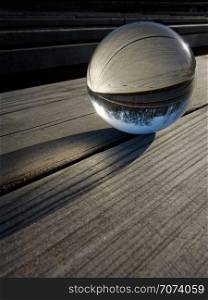 Backgrounds and textures: glass ball on a wooden table, part of a landscape inside. Glass ball refraction
