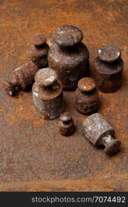 Backgrounds and textures: group of very old and rusty weights for scales, arranged on rusty surface.. Old weights for scales