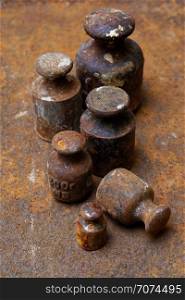 Backgrounds and textures: group of very old and rusty weights for scales, arranged on rusty surface.. Old weights for scales