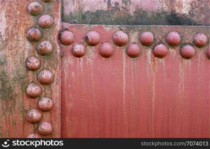 Backgrounds and textures: old painted metal wall surface with riveted joints, industrial abstract. Old riveted metal wall surface