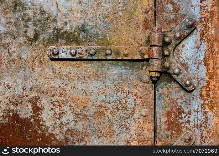Backgrounds and textures: rusty metal door surface with riveted hinges, industrial abstract. Rusty metal door details
