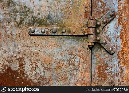 Backgrounds and textures: rusty metal door surface with riveted hinges, industrial abstract. Rusty metal door details