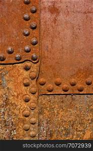 Backgrounds and textures: rusty metal surface with riveted joints, industrial abstract. Rusty metal wall surface