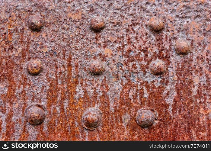 Backgrounds and textures: rusty metal wall surface with riveted joints, industrial abstract. Old riveted metal wall surface