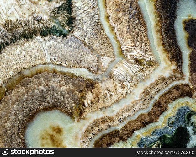 Backgrounds and textures: surface of beautiful brown-white decorative stone, abstract pattern of swirls, twirls, lines, cracks, spots and stains, natural background. Abstract mineral texture