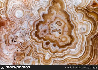 Backgrounds and textures: surface of beautiful brown-white decorative stone, abstract pattern of swirls, twirls, lines, cracks, spots and stains, natural background. Abstract mineral texture