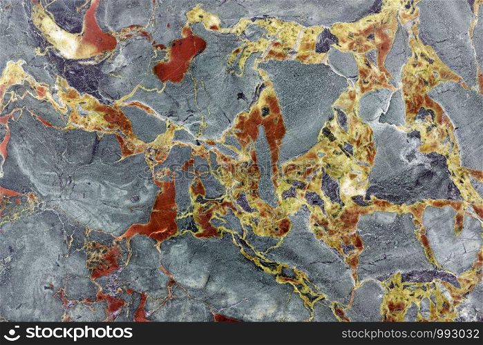 Backgrounds and textures: surface of beautiful grey decorative stone, abstract pattern of yellow and red cracks, spots and stains, natural background. Abstract mineral texture