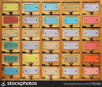 Backgrounds and textures: vintage wooden cabinet with drawers with multicolor labels. Vintage wooden cabinet with multicolor labels