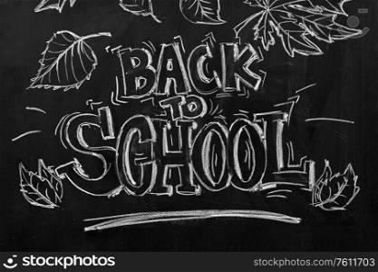 backgrounds, education and learning concept - back to school words and autumn leaves drawn with chalk on black chalkboard. back to school lettering drawn on chalkboard