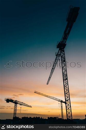 Backlit construction cranes at yard with copy space.. Backlit construction cranes at yard with copy space