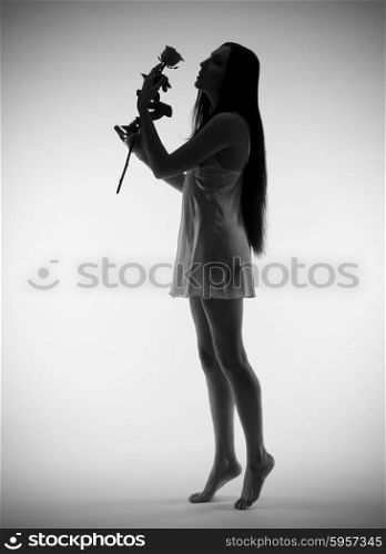Backlite portrait of young girl with rose on grey (monochrome version)