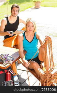 Backpack active young woman sitting by terrace hold climbing rope