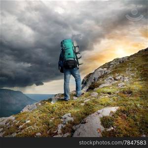 Backpacker in mountains under the thunder clouds