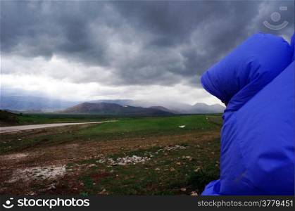 Backpacker with raincoat on the field before thunderstorm in Turkey
