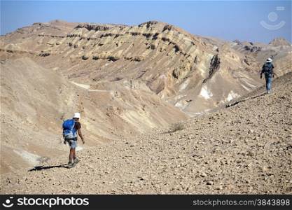Backpackers walk on the trail in crater Ramon, Israel
