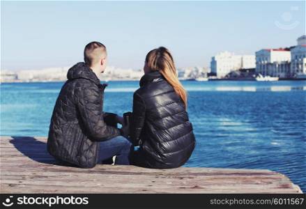 Backs of young couple sitting by the bay