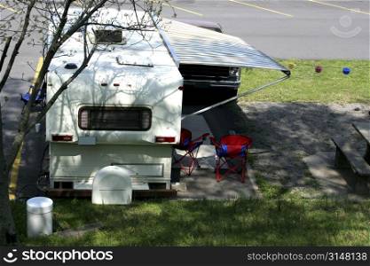 Backside of a camper and two chairs.