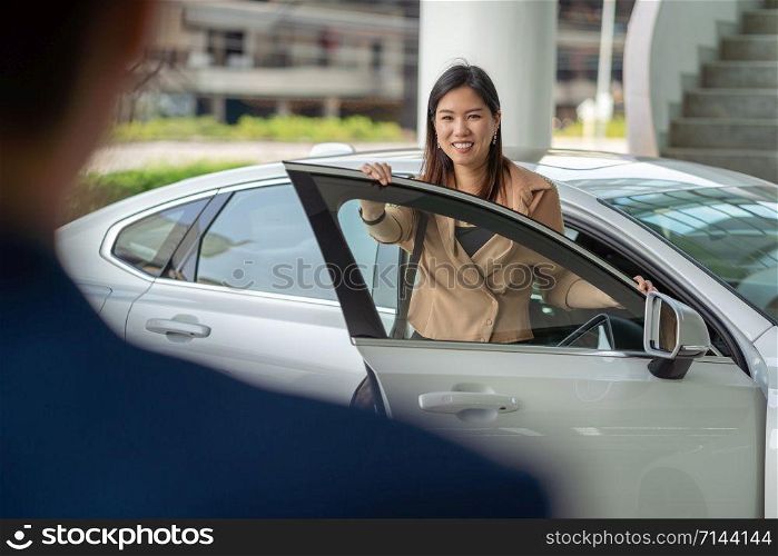 Backside of Receptionist welcoming the asian customer woman to visit maintainance service center for checking the car in showroom