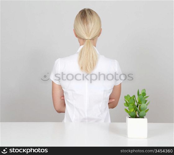 Backview of blond woman and plant in foreground