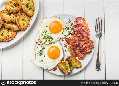 bacon and eggs for breakfast with chives and bread, top view,