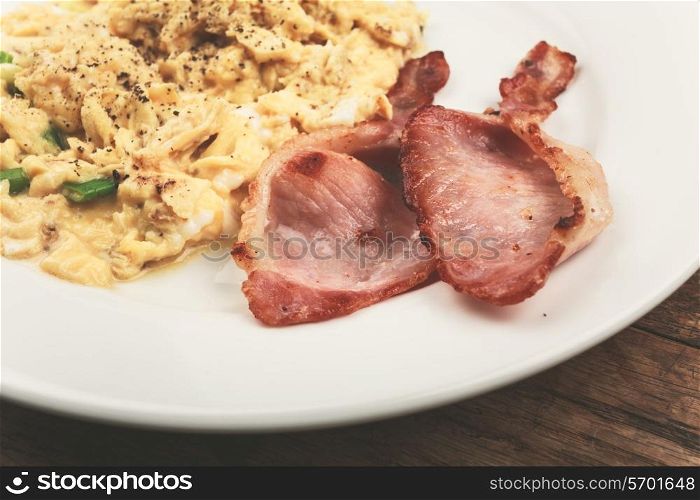 Bacon and scrambled eggs on a white plate