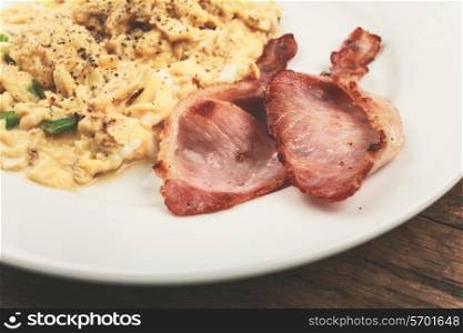 Bacon and scrambled eggs on a white plate