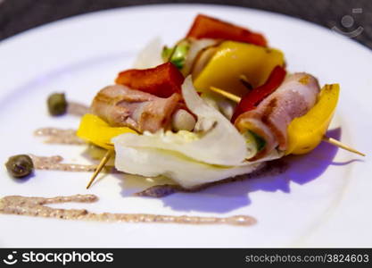 Bacon appetizer on stick with peppers and onions