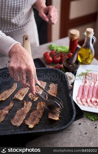 Bacon slices fying on grill frying pan Skillet at domestic kitchen.. Bacon slices fying on grill frying pan Skillet at domestic kitchen