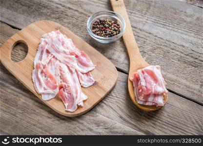 Bacon strips with pepper on wooden spoon
