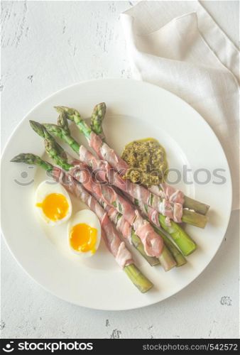Bacon wrapped asparagus dippers with pesto and soft-boiled egg on the table