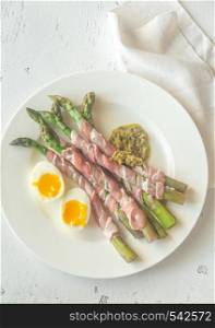 Bacon wrapped asparagus dippers with pesto and soft-boiled egg on the table