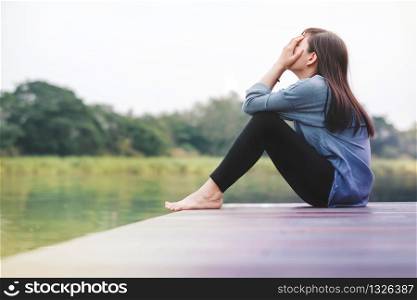 Bad Day Concept. Sadness Woman Sitting by the River on Wooden Patio Deck. Faceless with Full Length Body, Side View